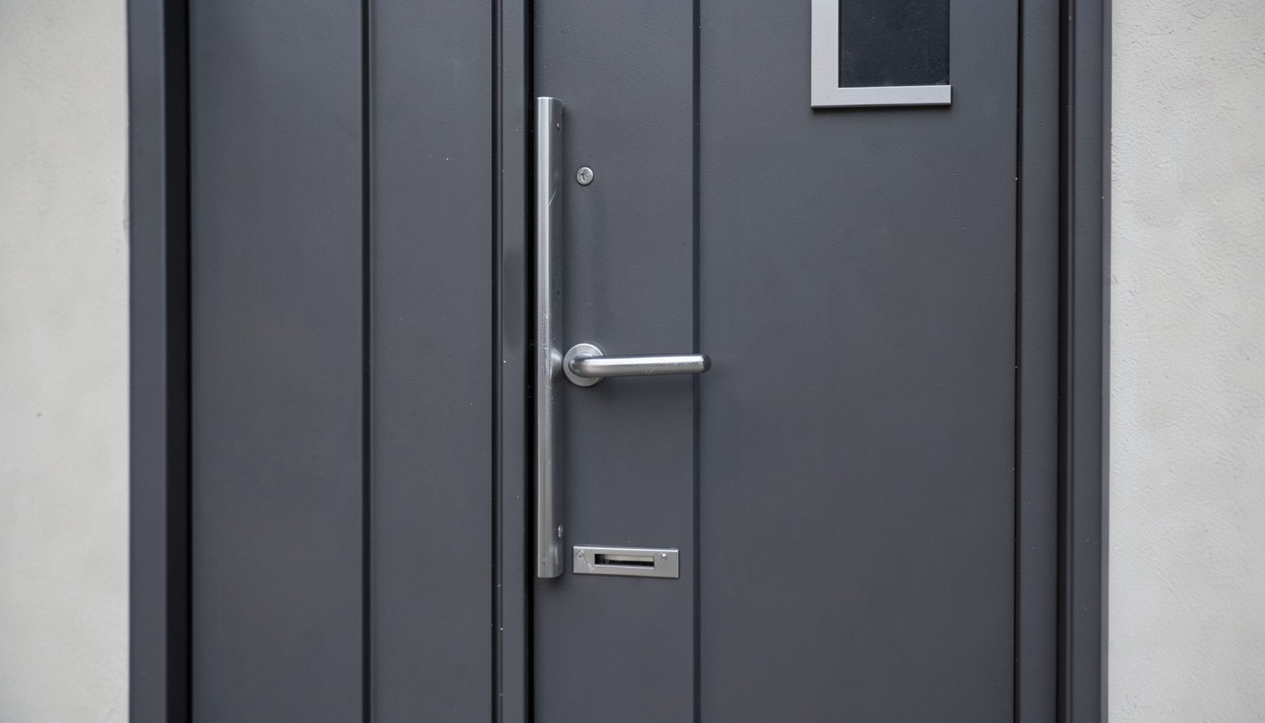 Close-up of a high-security composite door with chrome handle and letterbox, rich dark grey finish, solid and premium appearance
